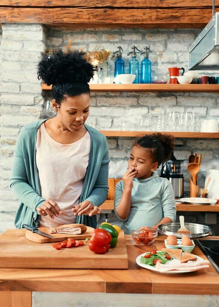 african american mother and daughter preparing a meal